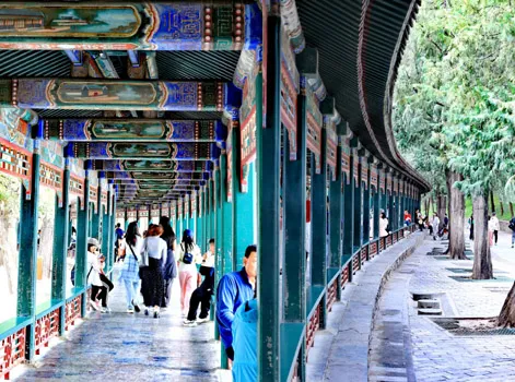 The Long Corridor with traditional Chinese paintings on beams, crowded with visitors walking through
